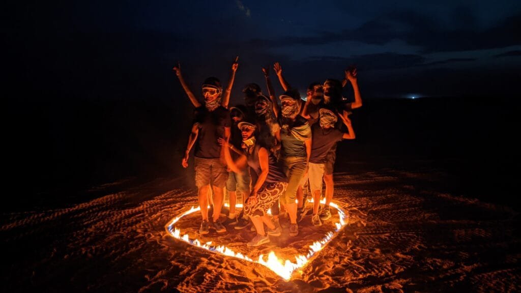 Visitors on a desert safari, making a heart of fire with Egypt Tour Magic.