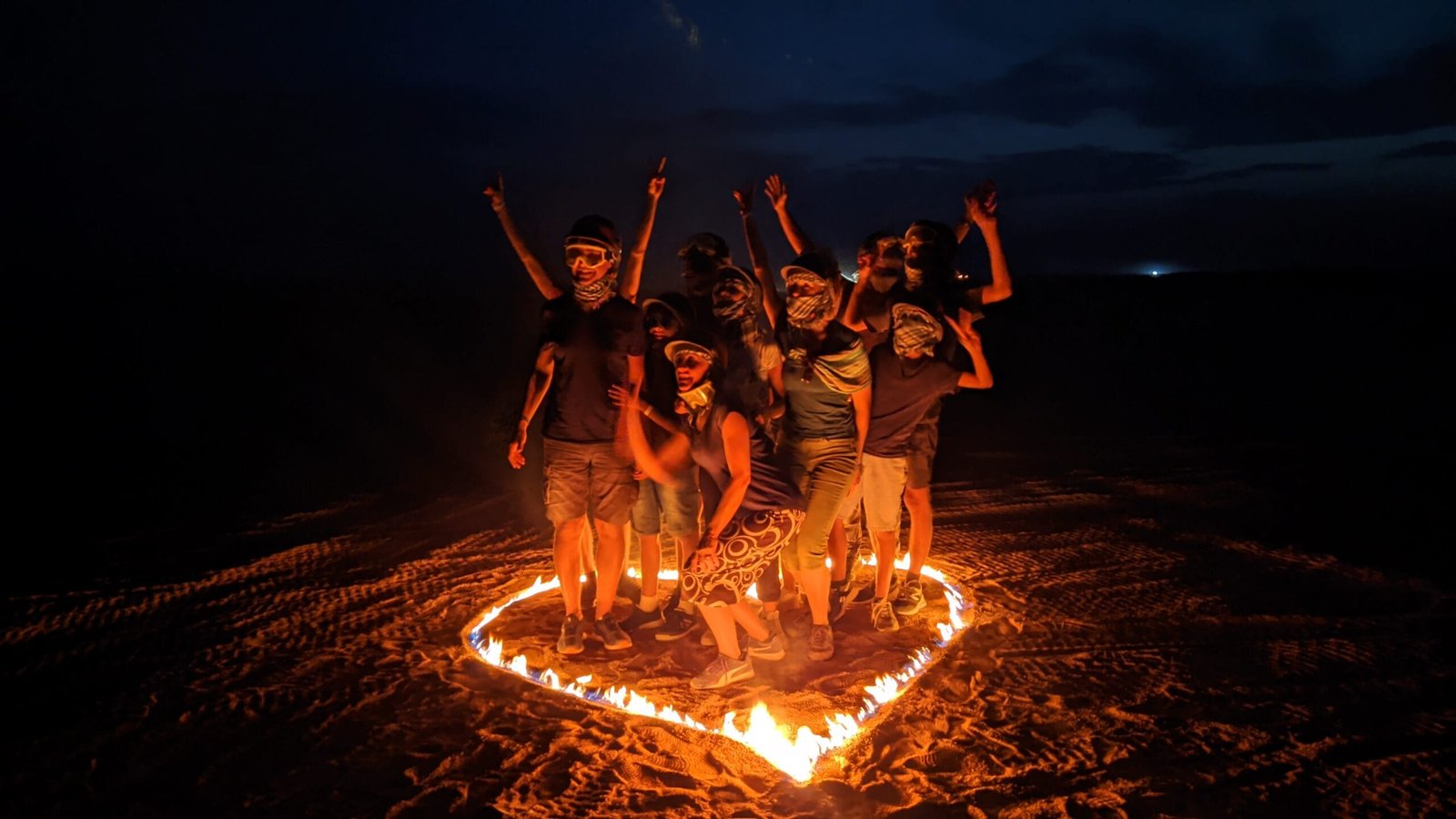 Visitors on a desert safari, making a heart of fire with Egypt Tour Magic.