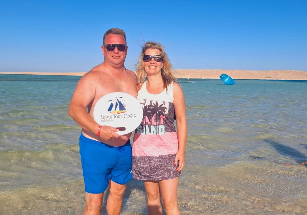 Two visitors on Mahmya Island, with one holding the Egypt Tour Magic logo.