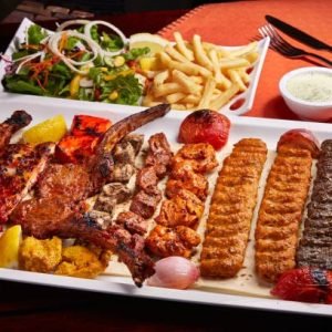 Spicy bbq Mixed Grills platter with tikka boti kababs, fries, salad and raita served in dish isolated on table side view of middle east food
